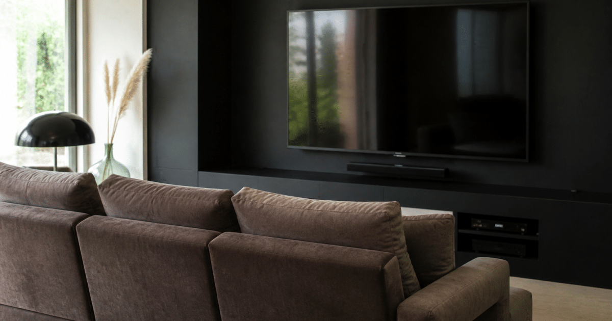 Canape rembourre face grand ecran mural noir