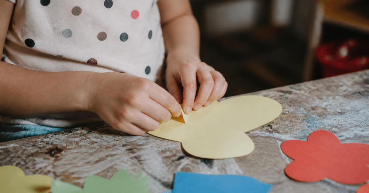 Mains pliant et collant des formes colorées en papier