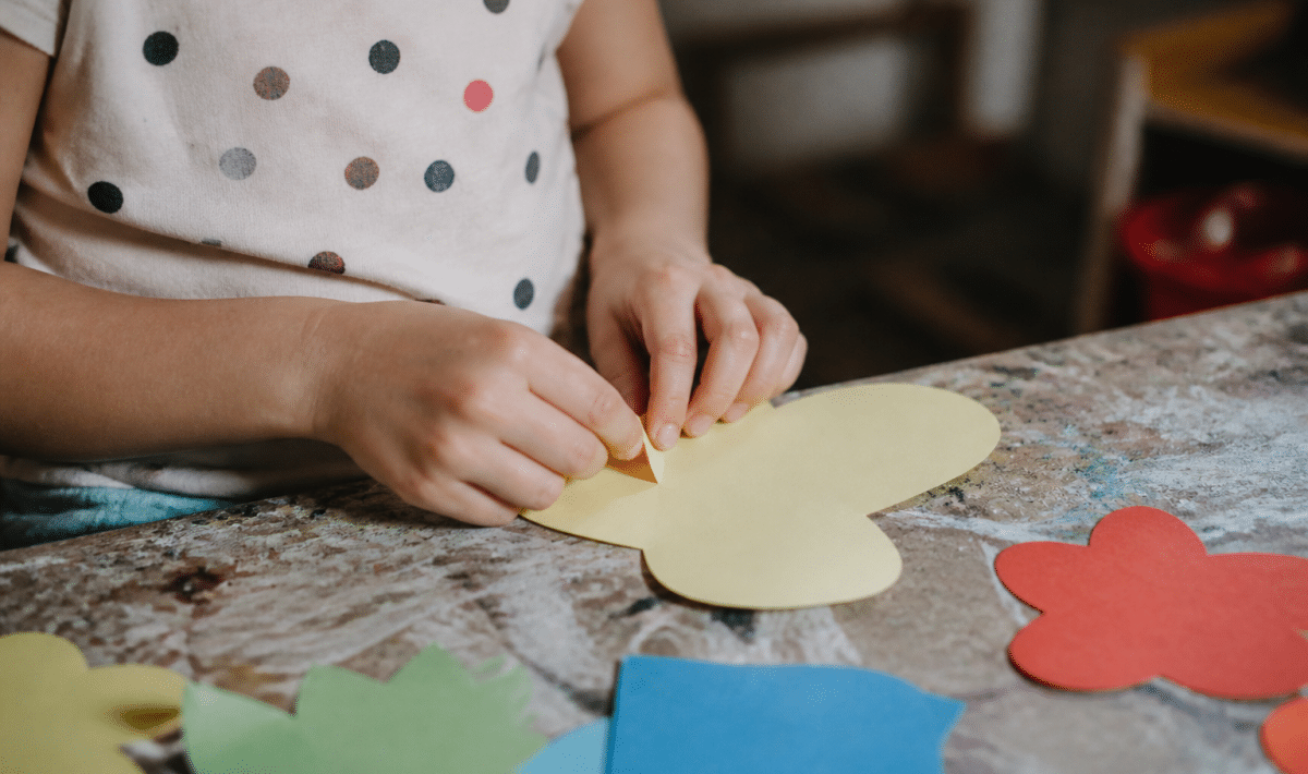 Mains pliant et collant des formes colorées en papier