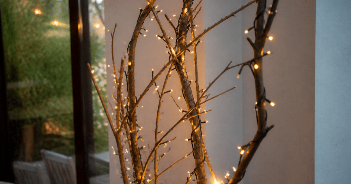 Guirlandes lumineuses enroulees autour de branches seches posees verticalement