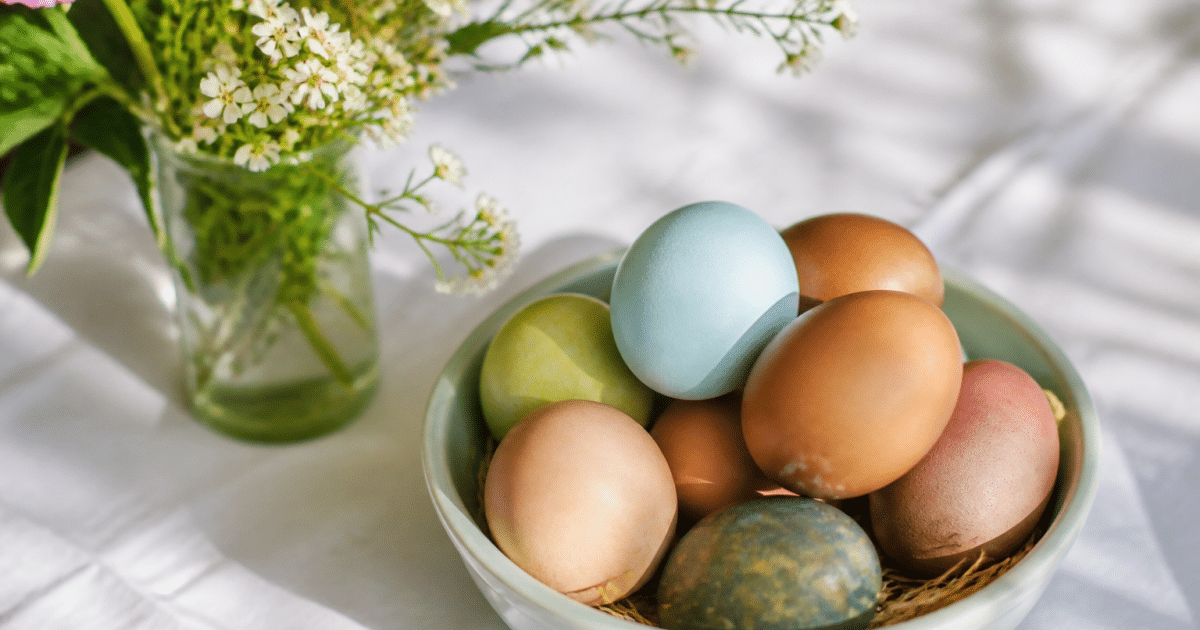 Oeufs colores et fleurs fraiches disposees sur nappe blanche