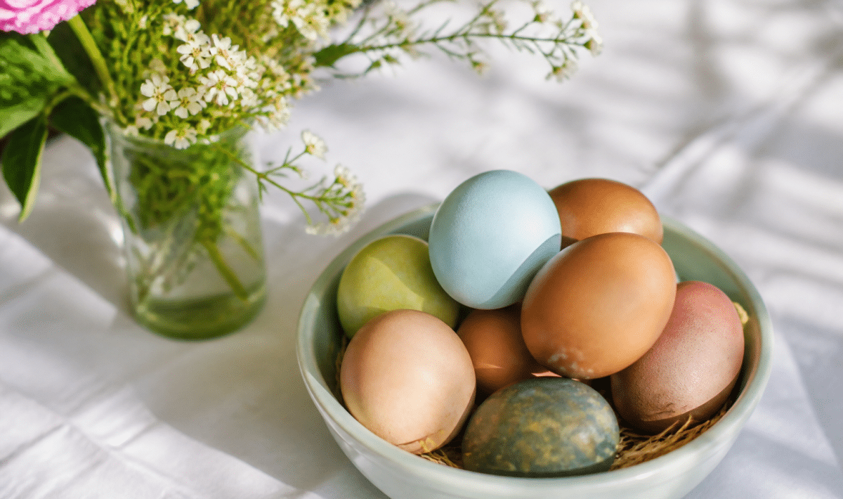 Oeufs colores et fleurs fraiches disposees sur nappe blanche