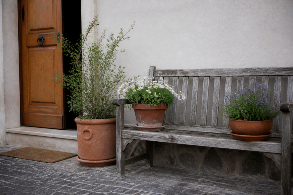 Banc sobre avec pots fleuris pres entree maison