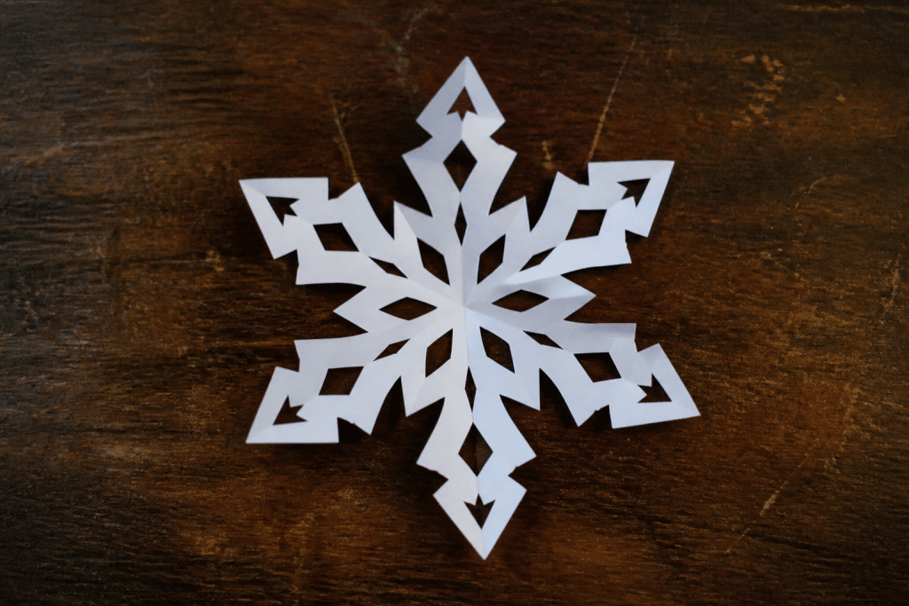 Flocon de neige blanc decoupé dans feuille pliée