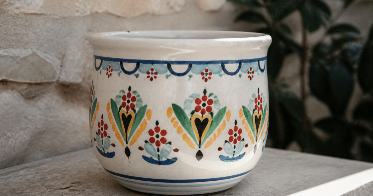 Pot ceramique blanc peint de motifs colorés posé sur surface