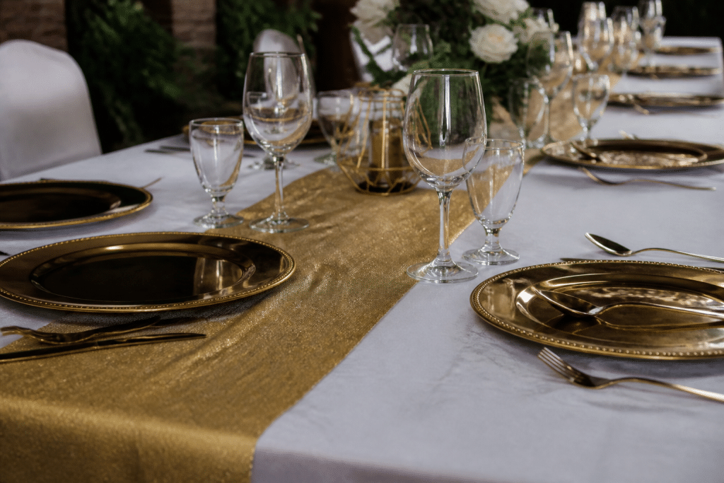 Nappe blanche avec chemin de table doré et vaisselle brillante