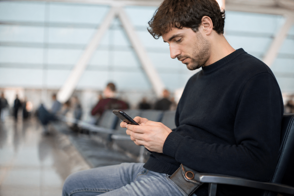 Voyageur verifiant telephone avec portefeuille securise en poche