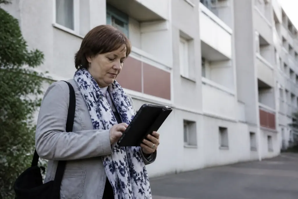 Agent recenseur tenant une tablette devant immeuble