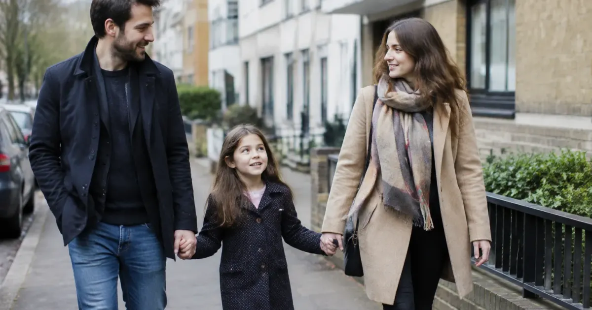 Une famille marche sur un trottoir devant des immeubles