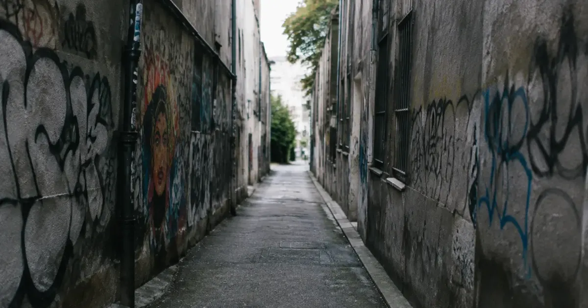 Rue sombre aux murs gris couverts graffitis