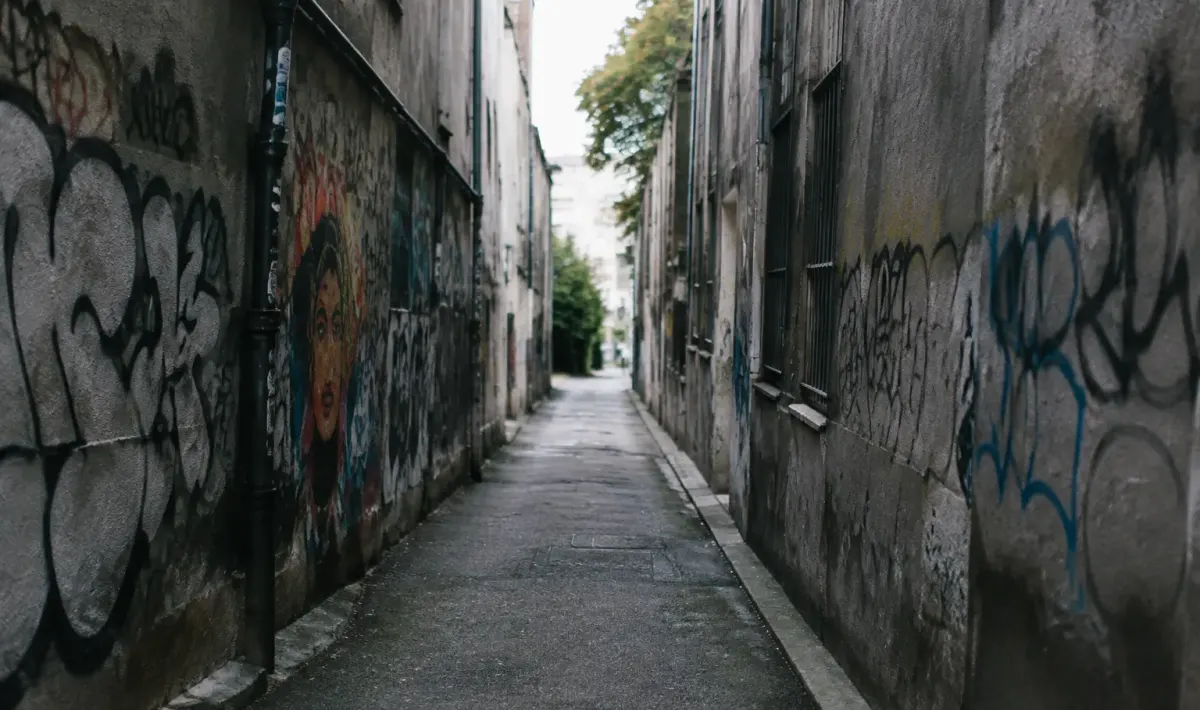 Rue sombre aux murs gris couverts graffitis